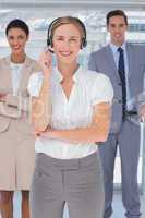 Cheerful woman with headset standing in front of business people