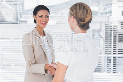 Two smiling colleagues shaking hands