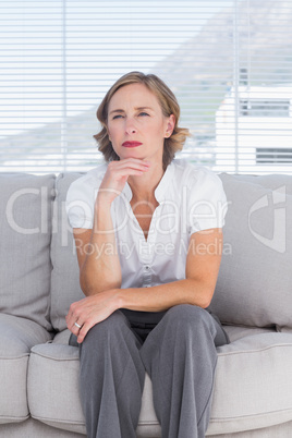 Thinking businesswoman sitting on couch