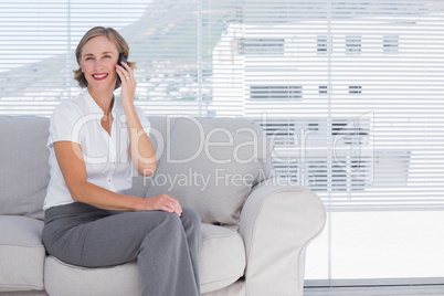 Smiling businesswoman sitting calling in the office