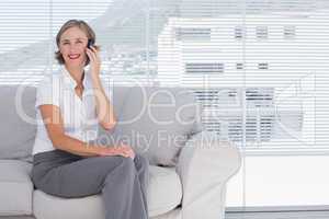 Smiling businesswoman sitting calling in the office