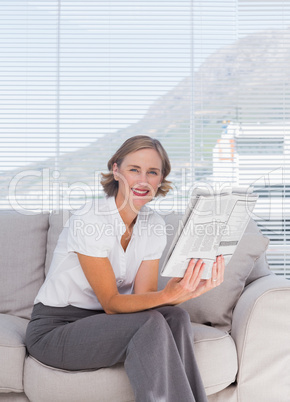 Businesswoman sitting on couch and holding newspaper