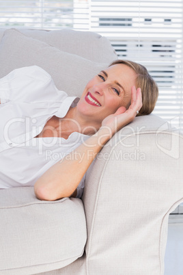 Cheerful businesswoman lying on sofa