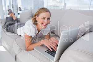 Businesswoman lying on couch using her laptop