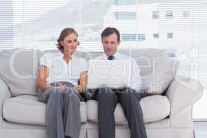 Business people sitting on couch and using laptop