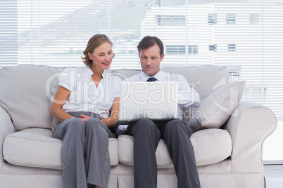 Businessman pointing something on laptop to her colleague