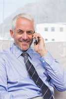 Smiling businessman calling on smartphone