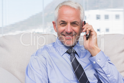 Businessman calling on smartphone and smiling at camera