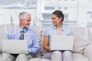 Business people using their laptops and smiling at each other