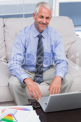 Businessman working with his laptop and smiling at camera