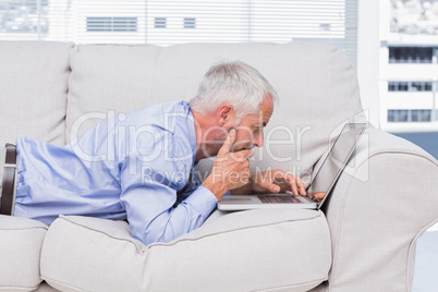 Businessman lying on sofa with laptop