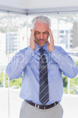 Stressed businessman rubbing his temples with eyes closed