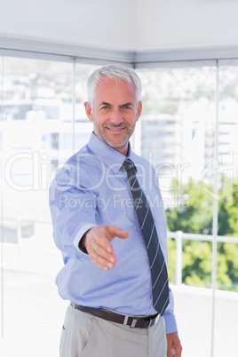 Smiling businessman extending arm for handshake