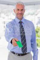 Happy businessman giving green business card
