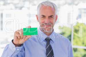 Happy businessman showing green business card