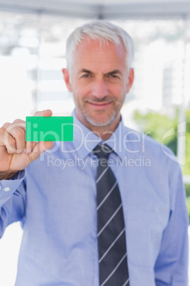 Smiling businessman showing green business card