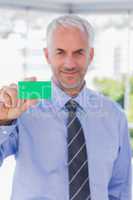 Smiling businessman showing green business card