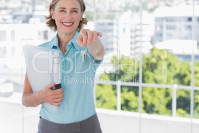 Estate agent showing house keys and smiling at camera