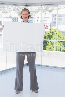 Smiling businesswoman holding large white poster