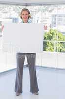 Smiling businesswoman holding large white poster