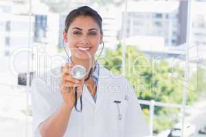 Smiling young doctor holding up stethoscope