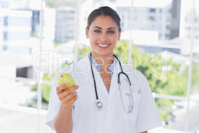 Smiling young doctor holding a green apple