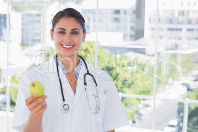 Smiling doctor holding a green apple