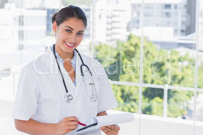 Doctor smiling and holding clipboard and pen