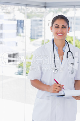 Doctor smiling at camera and holding clipboard and pen