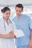 Doctor and surgeon reading over notes on clipboard