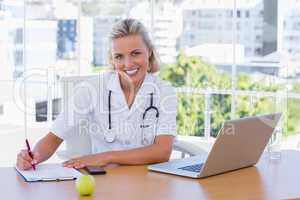 Beautiful nurse writing on a notepad on her desk