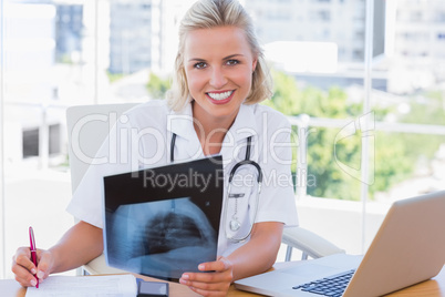 Cheerful nurse holding an x ray in her office