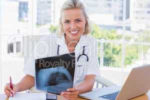 Cheerful nurse holding an x ray in her office