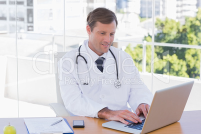 Happy doctor working on a laptop