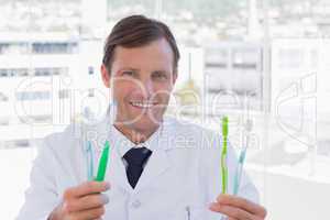 Happy doctor holding two toothbrushes