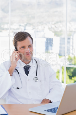 Cheerful doctor phoning in his office