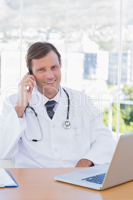 Smiling doctor phoning in his office