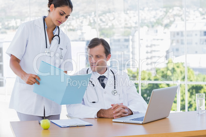 Doctor showing a folder to a colleague