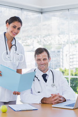 Smiling doctor showing a folder to a colleague