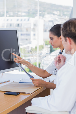 Beautiful nurse showing the screen of a computer to a colleague