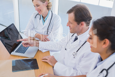 Smiling doctor showing laptop screen to colleagues