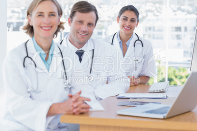 Happy doctors posing at their desk