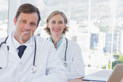 Cheerful group of doctors posing at their desk