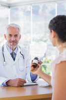 Patient holding a bottle of pills in front of doctor