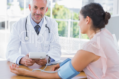 Smiling doctor taking the heartbeat of a patient