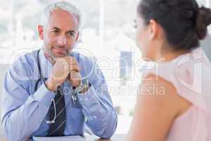 Serious doctor listening to patient explaining her painful