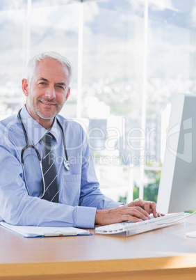 Smiling doctor typing on his computer