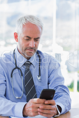 Doctor typing a text message on his smartphone