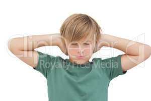 Blonde boy covering his ears with his eyes closed