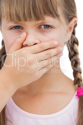Portrait of a little blond girl with her hand on her mouth